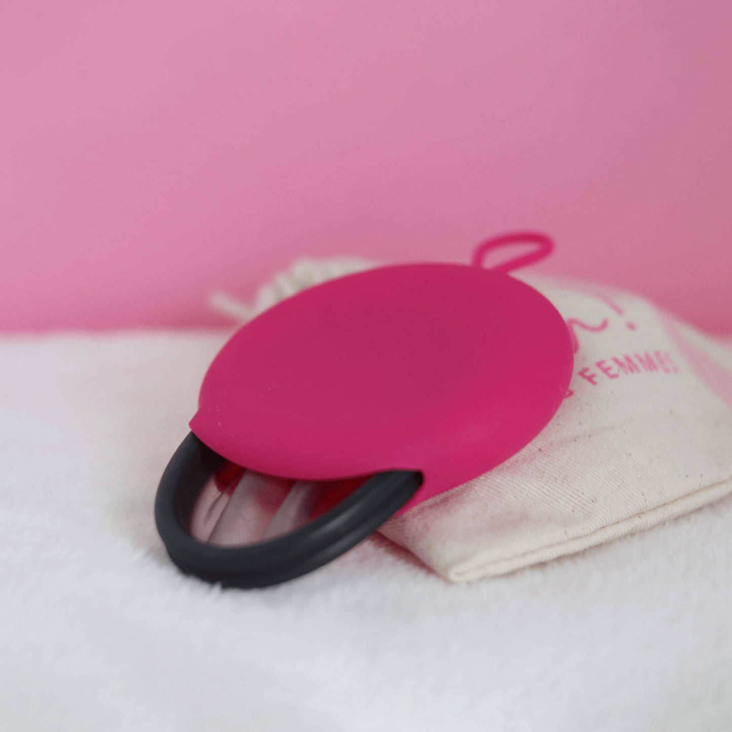Disque menstruel réutilisable discoh noir taille L dans sa pochette en silicone fushia. Alternative aux tampons et serviettes, nouvelle alternative zero déchet