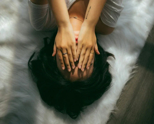 Portrait d’une femme avec les mains sur le visage, illustrant la fatigue ou l’inconfort des règles