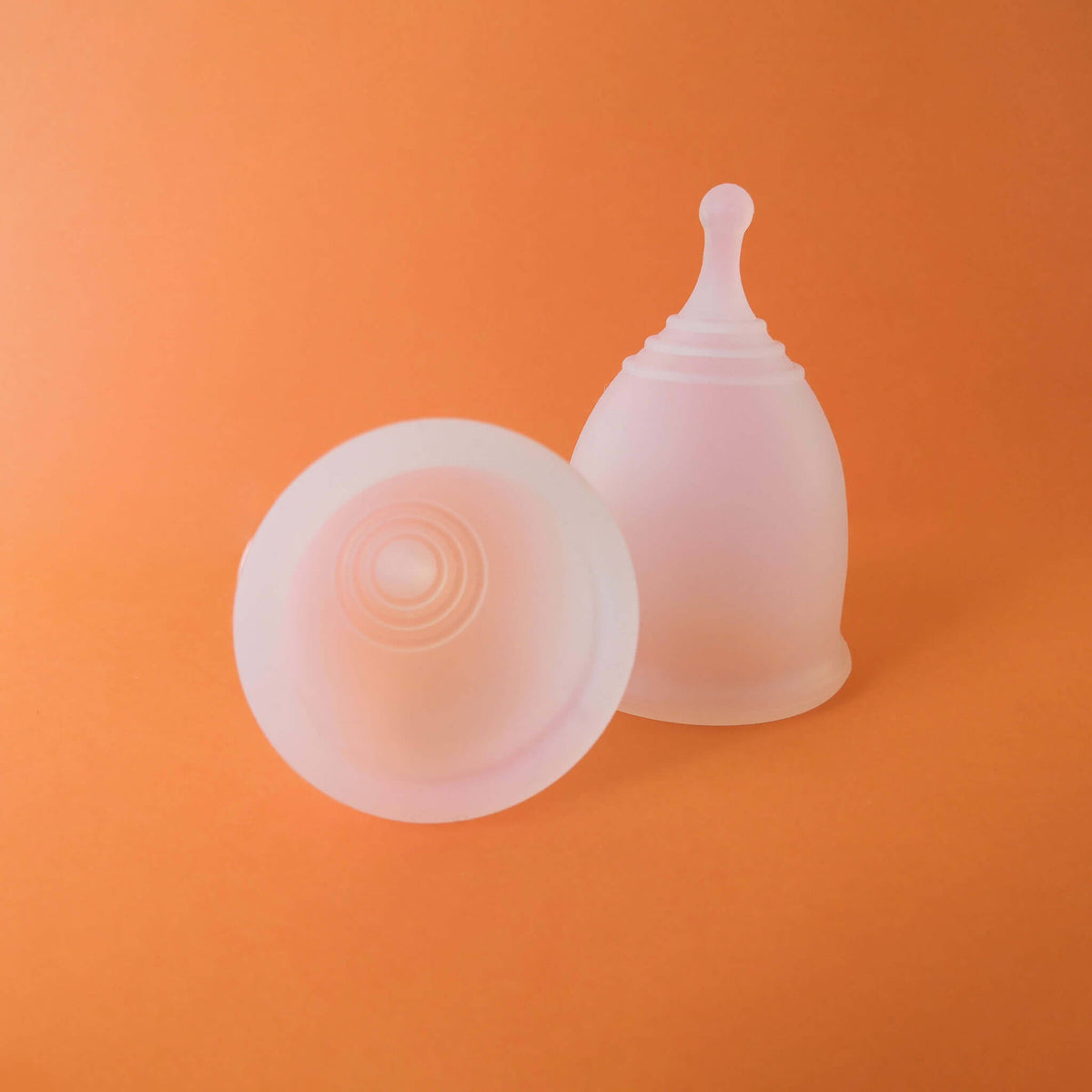 Coupe menstruelle Cup'Oh en silicone médical transparent sur fond orange