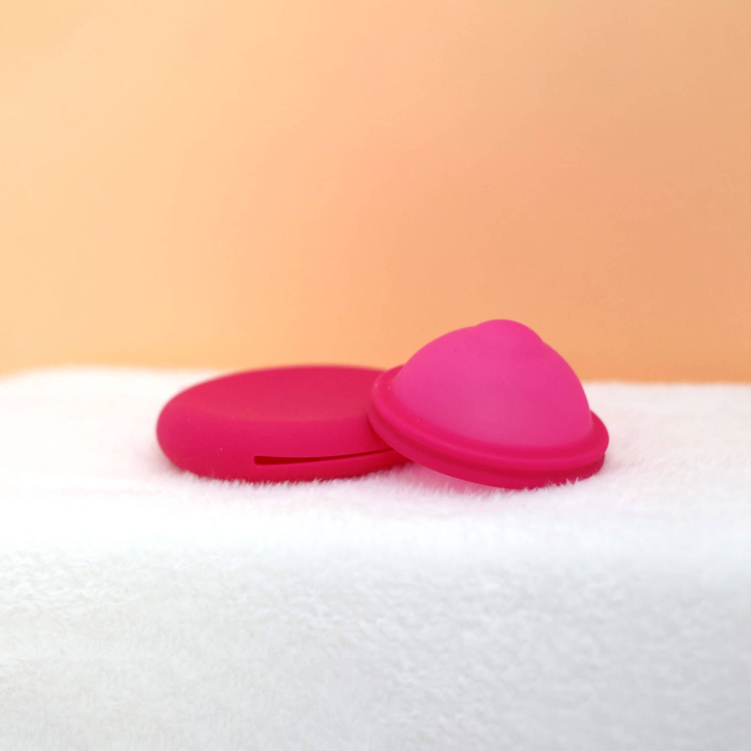 Disque menstruel discoh coloris fuchsia taille S. Sur fond crème posé sur sa pochette en silicone