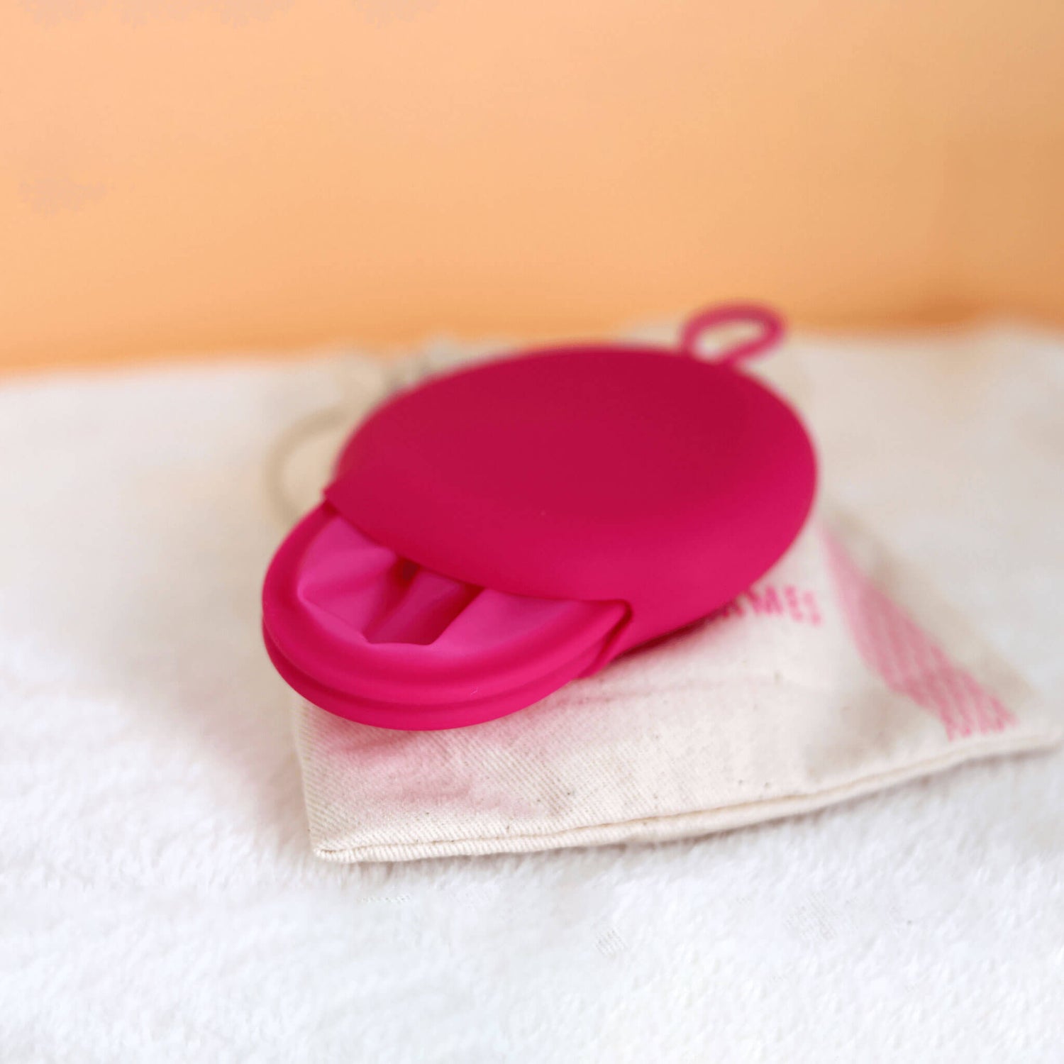 Disque menstruel discoh taille S coloris fushia a moitié inséré dans sa pochette en silicone